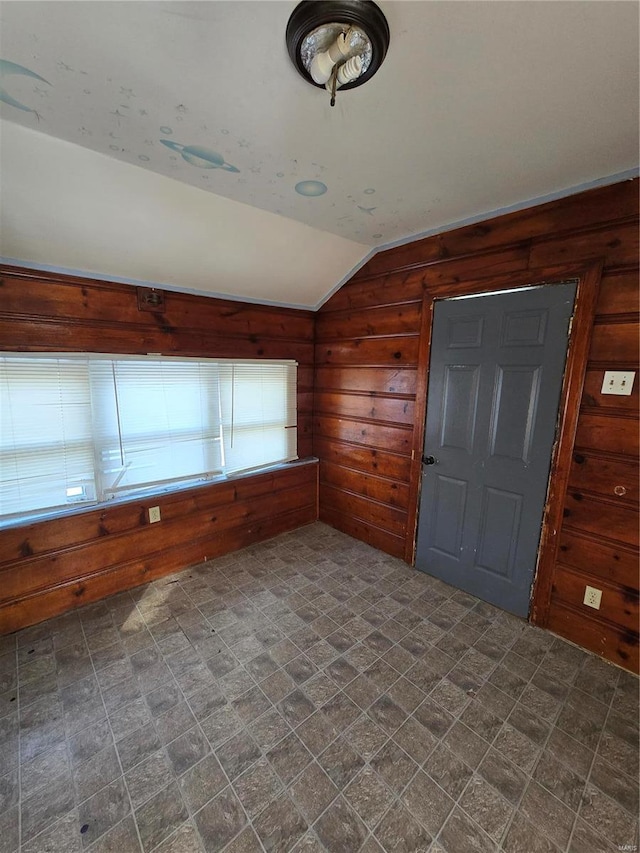 interior space featuring lofted ceiling and wood walls