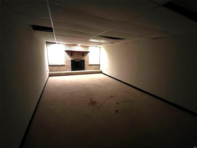 basement featuring a drop ceiling and a brick fireplace