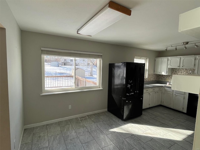 kitchen featuring decorative backsplash, white cabinets, freestanding refrigerator, and baseboards