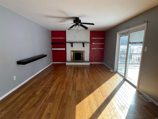 unfurnished living room with visible vents, a brick fireplace, baseboards, and wood-type flooring