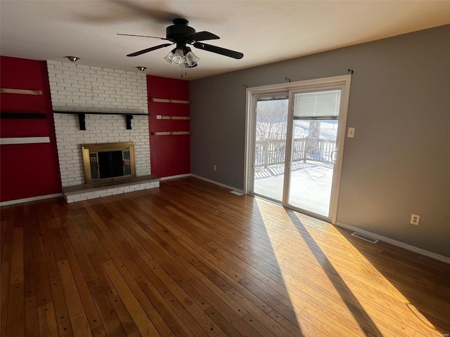 unfurnished living room with visible vents, baseboards, a brick fireplace, and hardwood / wood-style flooring