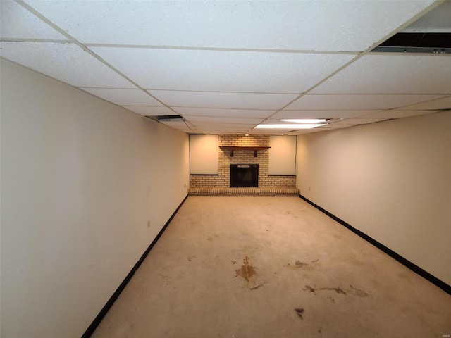 finished below grade area featuring a fireplace, a paneled ceiling, and baseboards