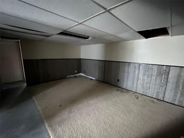 basement with wainscoting and a paneled ceiling