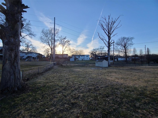 view of yard featuring an outbuilding, a storage shed, and fence