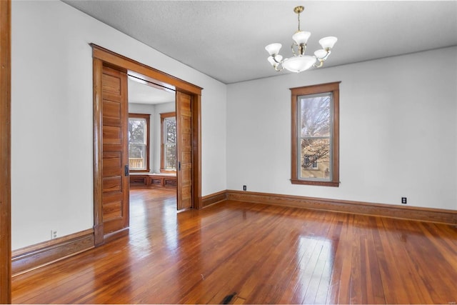 spare room featuring hardwood / wood-style floors and an inviting chandelier