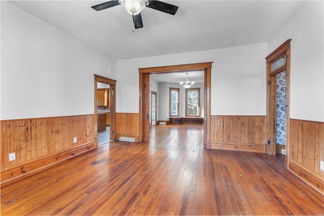 empty room with dark wood-type flooring and ceiling fan with notable chandelier