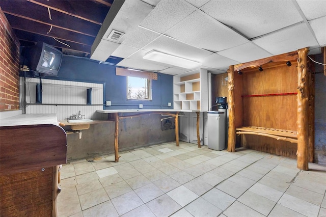 basement with sink, built in features, and a drop ceiling