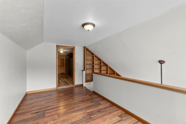 bonus room featuring built in shelves, dark hardwood / wood-style flooring, and vaulted ceiling