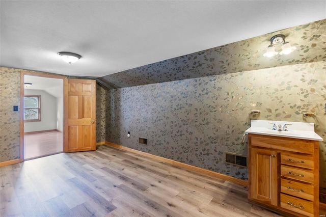 interior space featuring sink, light wood-type flooring, and lofted ceiling