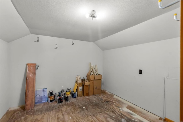 interior space featuring a textured ceiling and vaulted ceiling