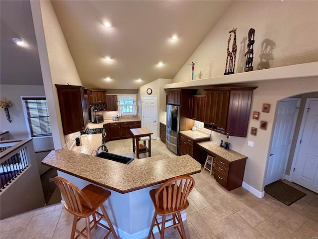 kitchen featuring sink, a center island, stainless steel fridge, a kitchen breakfast bar, and kitchen peninsula