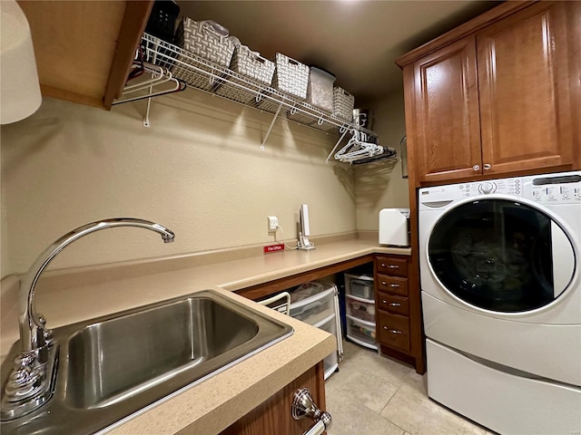 laundry area featuring sink, light tile patterned floors, washer / clothes dryer, and cabinets