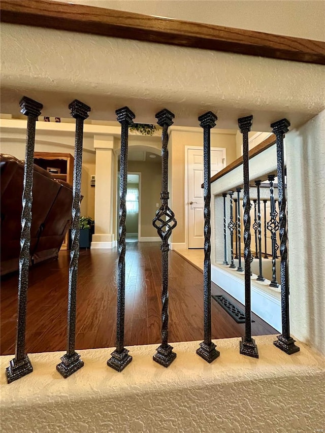 interior details with wood-type flooring, decorative columns, and a textured ceiling