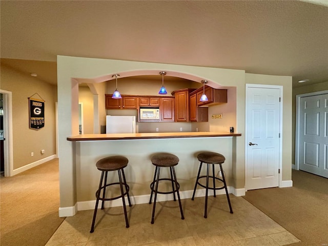 kitchen with white appliances, a kitchen breakfast bar, decorative light fixtures, and kitchen peninsula