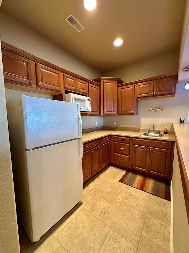 kitchen with sink, white appliances, and decorative light fixtures