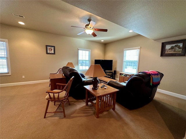 living room with ceiling fan, a healthy amount of sunlight, light carpet, and a textured ceiling