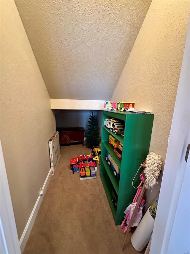 playroom featuring carpet, lofted ceiling, and a textured ceiling