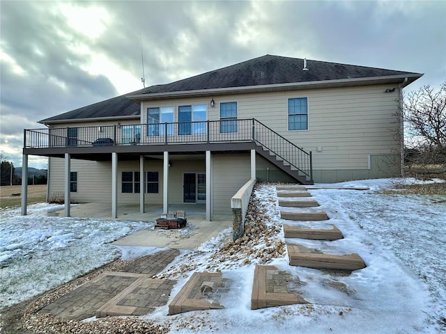 snow covered rear of property featuring a wooden deck and a fire pit