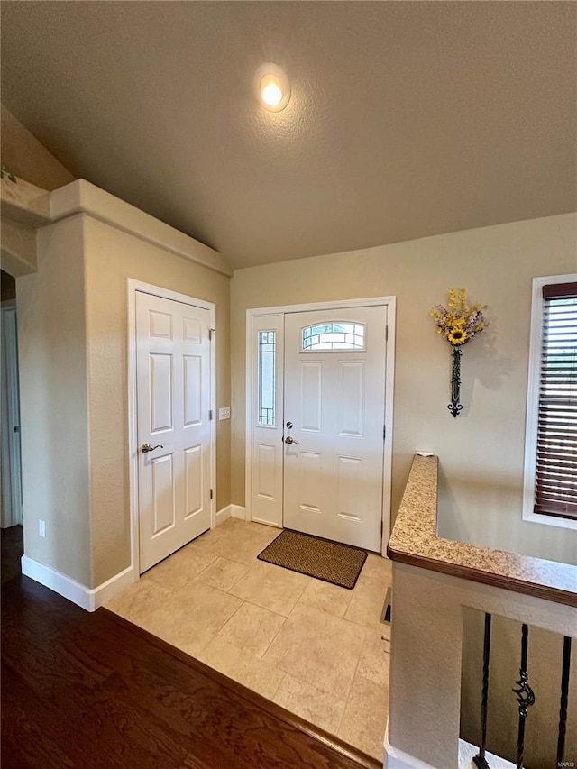 foyer entrance featuring vaulted ceiling and a textured ceiling