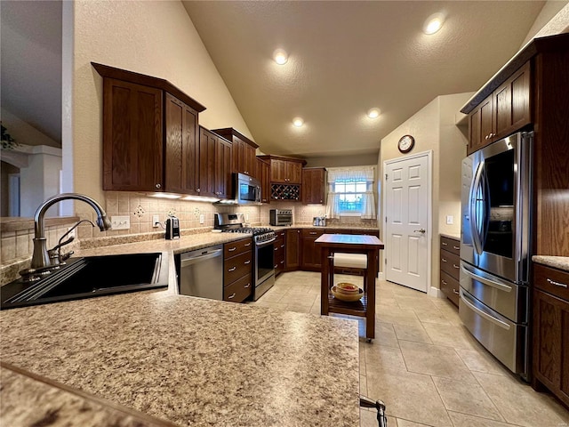 kitchen featuring light tile patterned flooring, appliances with stainless steel finishes, tasteful backsplash, lofted ceiling, and sink