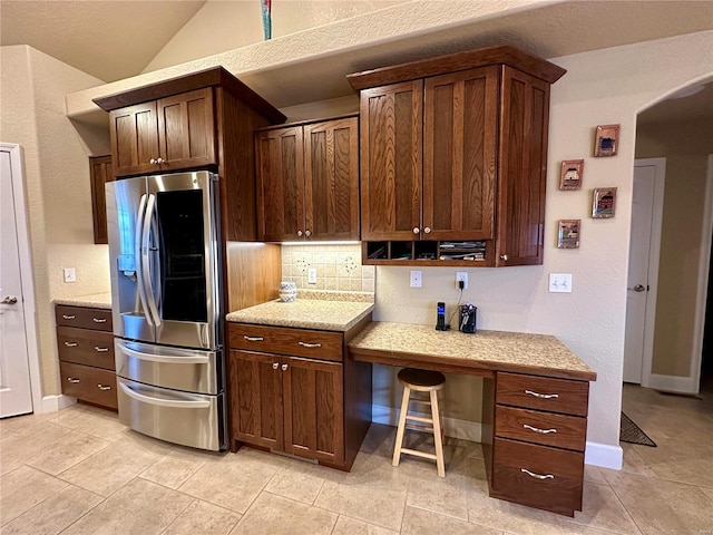 kitchen featuring tasteful backsplash, dark brown cabinets, vaulted ceiling, and stainless steel refrigerator with ice dispenser