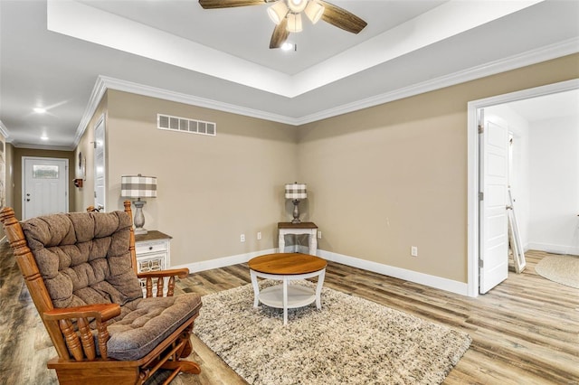 sitting room with ceiling fan, a raised ceiling, crown molding, and hardwood / wood-style flooring