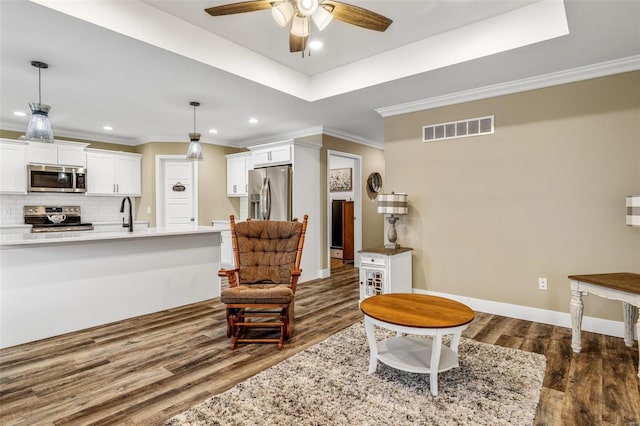 sitting room with ceiling fan, dark hardwood / wood-style floors, crown molding, and a raised ceiling