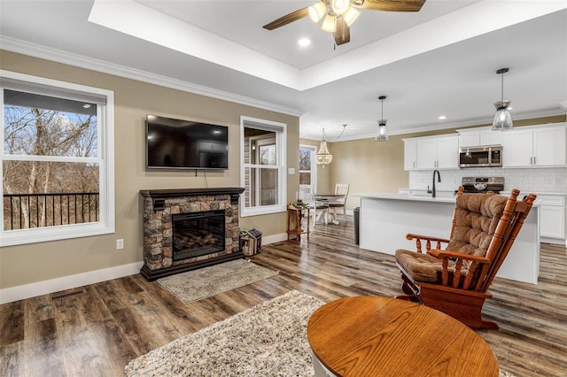 living room featuring a raised ceiling, dark hardwood / wood-style flooring, crown molding, and a fireplace