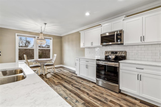 kitchen featuring hanging light fixtures, decorative backsplash, stainless steel appliances, and white cabinetry