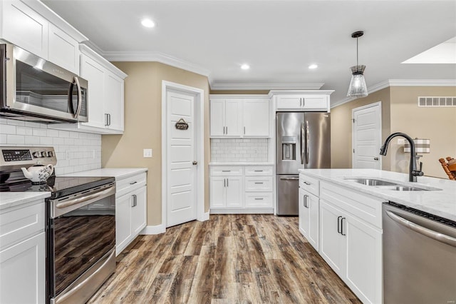 kitchen with white cabinetry, stainless steel appliances, light stone countertops, ornamental molding, and sink