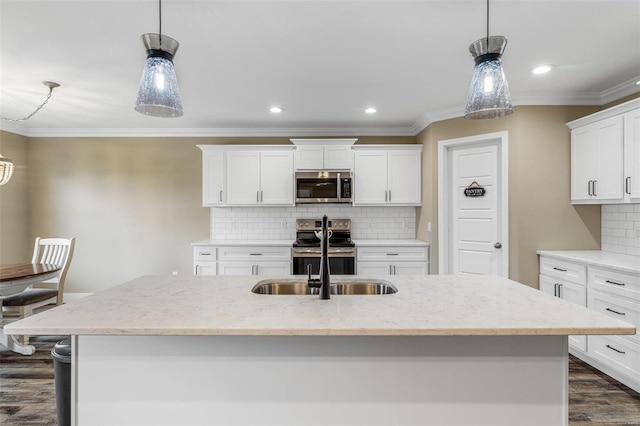 kitchen with stainless steel appliances, backsplash, a kitchen island with sink, decorative light fixtures, and white cabinets