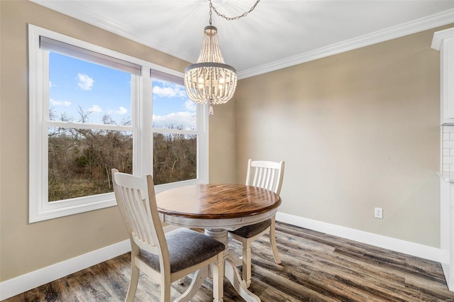 dining room with dark wood-type flooring, ornamental molding, and an inviting chandelier