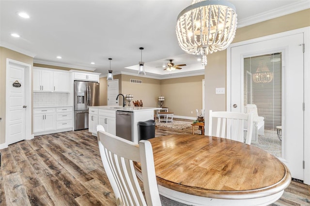 dining area with ornamental molding, ceiling fan with notable chandelier, hardwood / wood-style flooring, and sink