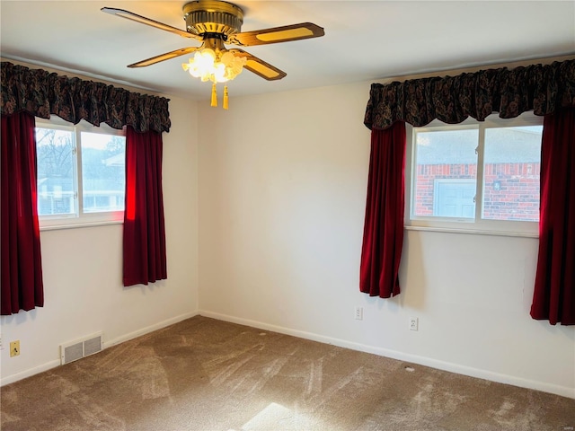 spare room with ceiling fan, carpet flooring, visible vents, and baseboards