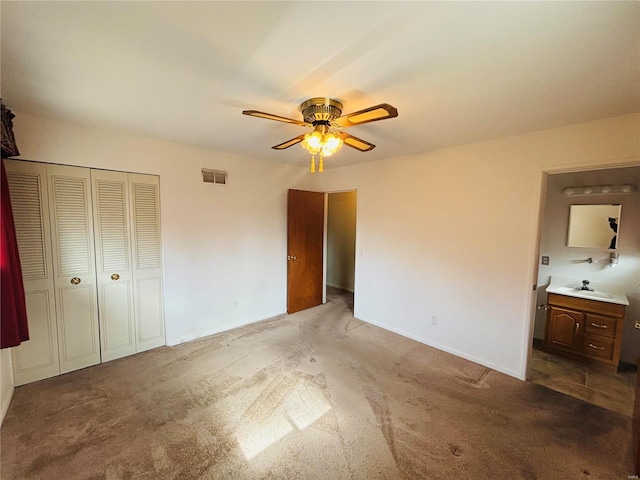 unfurnished bedroom with a closet, visible vents, a ceiling fan, light colored carpet, and a sink