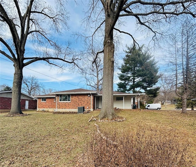 view of front of house with central air condition unit, a front lawn, and brick siding