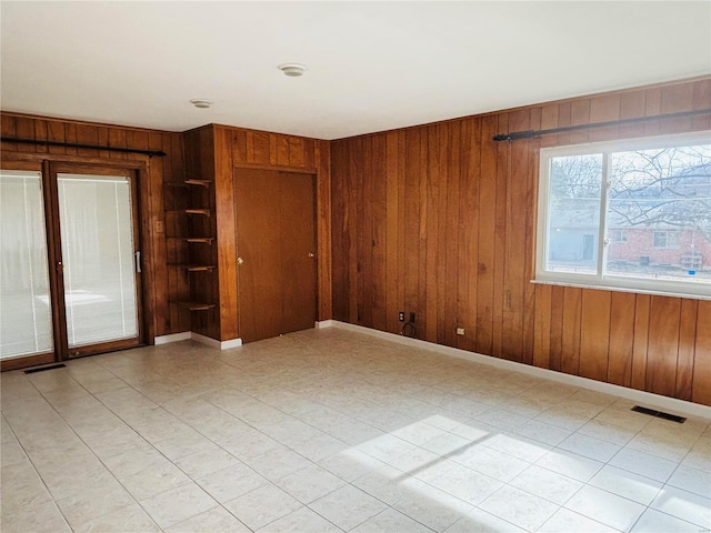 spare room with baseboards, visible vents, and wooden walls