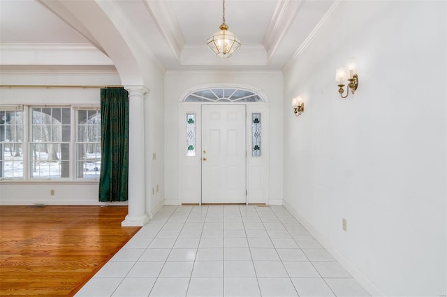 tiled foyer with ornamental molding, ornate columns, and a tray ceiling