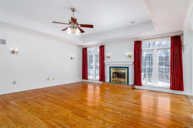 unfurnished living room featuring light wood-type flooring, a raised ceiling, and crown molding