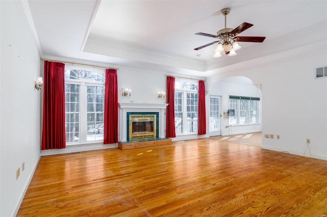 unfurnished living room featuring crown molding, hardwood / wood-style flooring, a wealth of natural light, and a tray ceiling