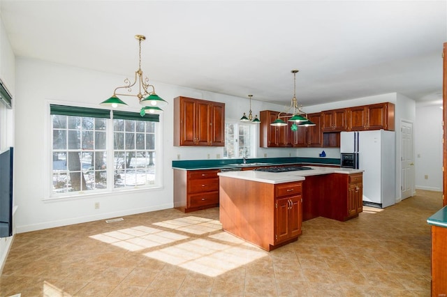 kitchen featuring a kitchen island, white fridge with ice dispenser, pendant lighting, and gas cooktop