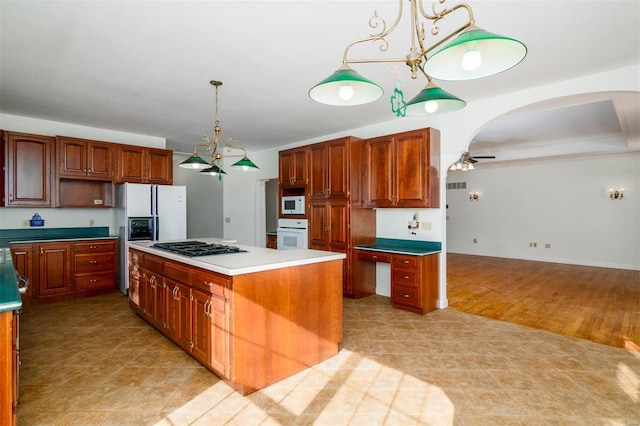 kitchen featuring light hardwood / wood-style flooring, ceiling fan, decorative light fixtures, white appliances, and a center island