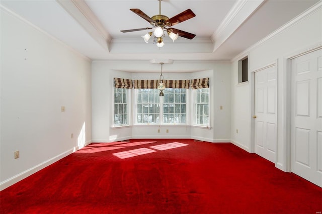 unfurnished dining area featuring ceiling fan, ornamental molding, carpet floors, and a tray ceiling