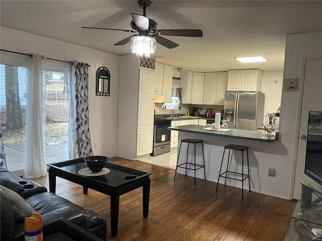 kitchen featuring stainless steel fridge, visible vents, range, light wood-style flooring, and a peninsula