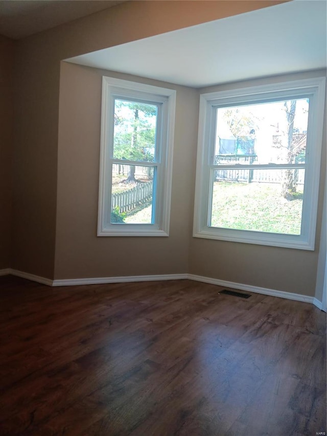 unfurnished room with a healthy amount of sunlight and dark hardwood / wood-style floors