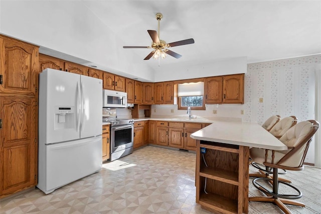 kitchen with sink, white appliances, kitchen peninsula, and ceiling fan