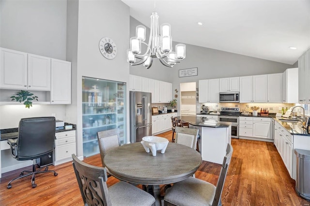 dining area with sink, a notable chandelier, high vaulted ceiling, and light hardwood / wood-style flooring