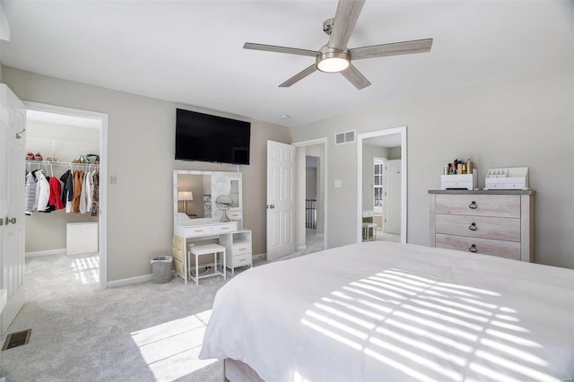 carpeted bedroom with a walk in closet, ceiling fan, and a closet