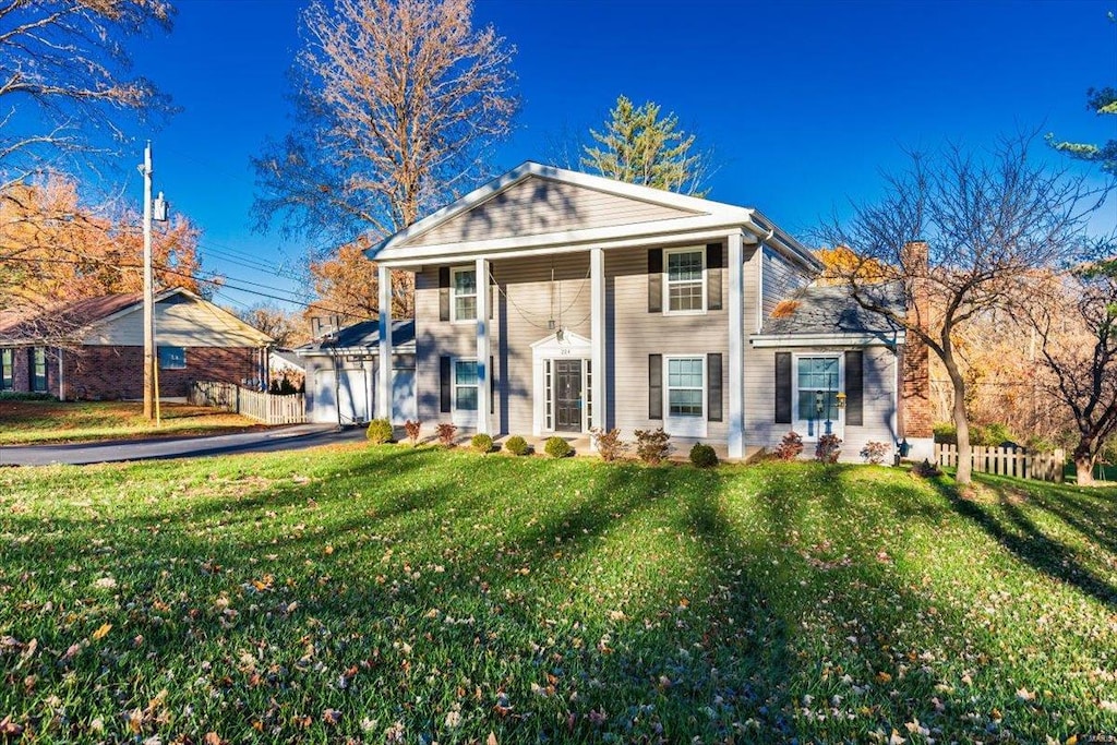 neoclassical home featuring a garage and a front lawn