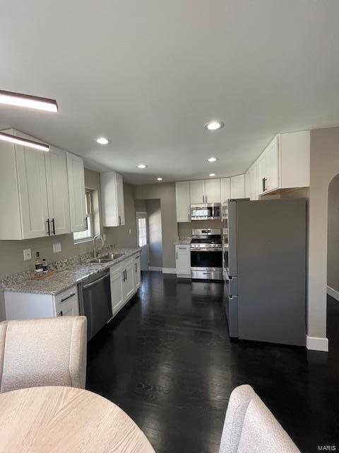 kitchen featuring white cabinetry, appliances with stainless steel finishes, sink, and light stone counters